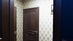 Una habitación con puerta de madera, papel tapiz estampado y suelo de color claro.