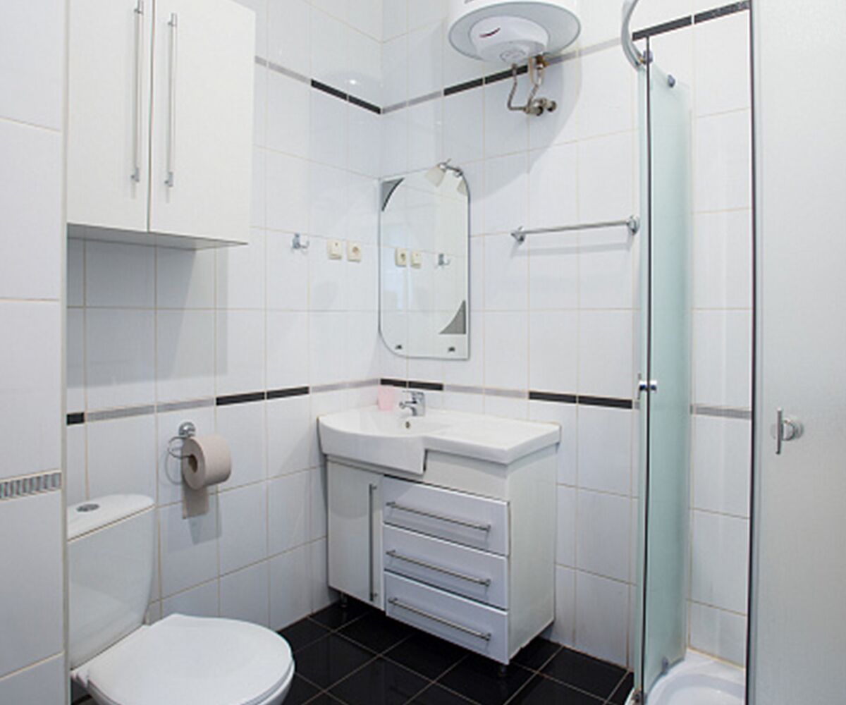 Een moderne badkamer met toilet, wastafel, spiegel en douche.