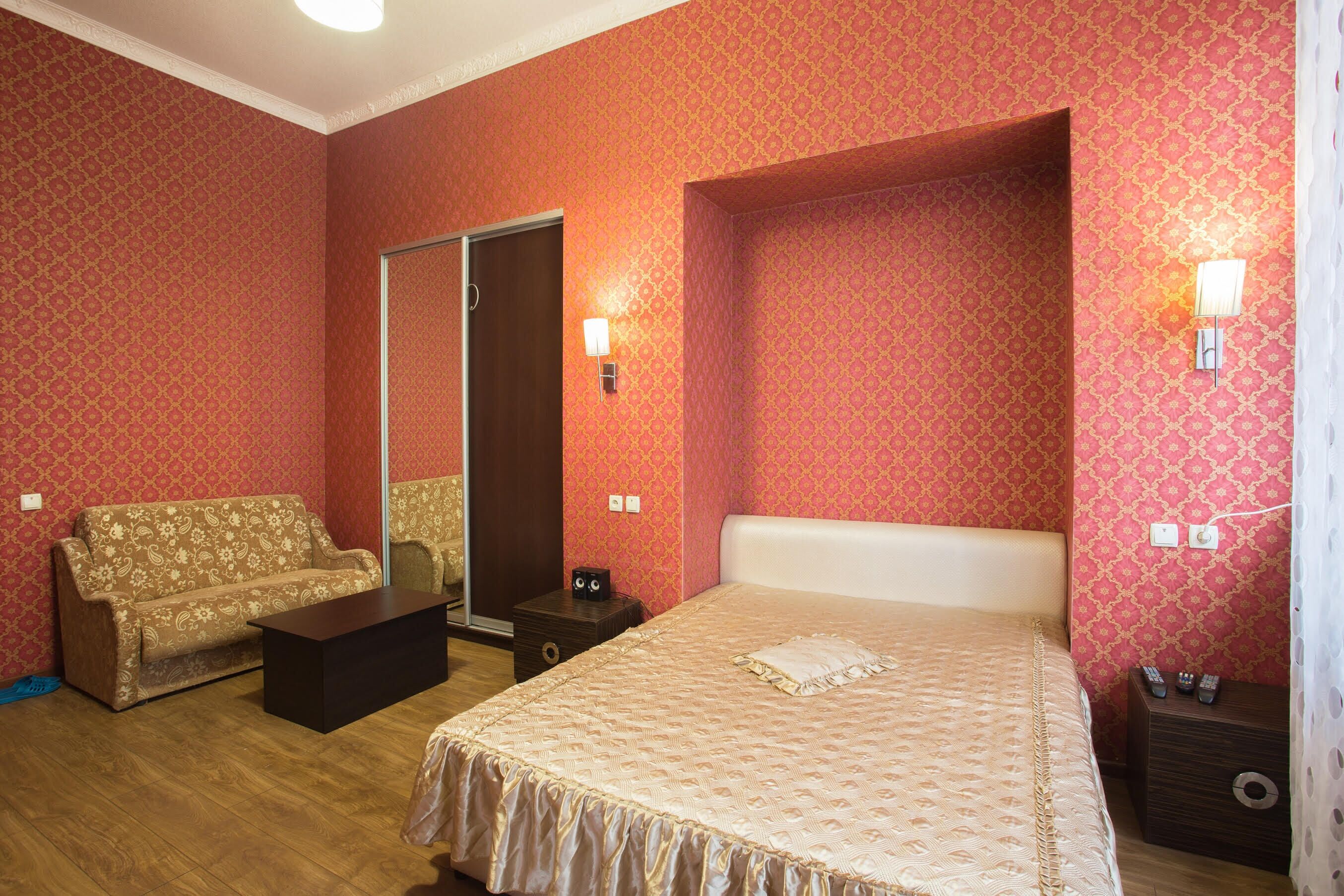 Una habitación de hotel con cama, sofá, una mesita y un buró.
