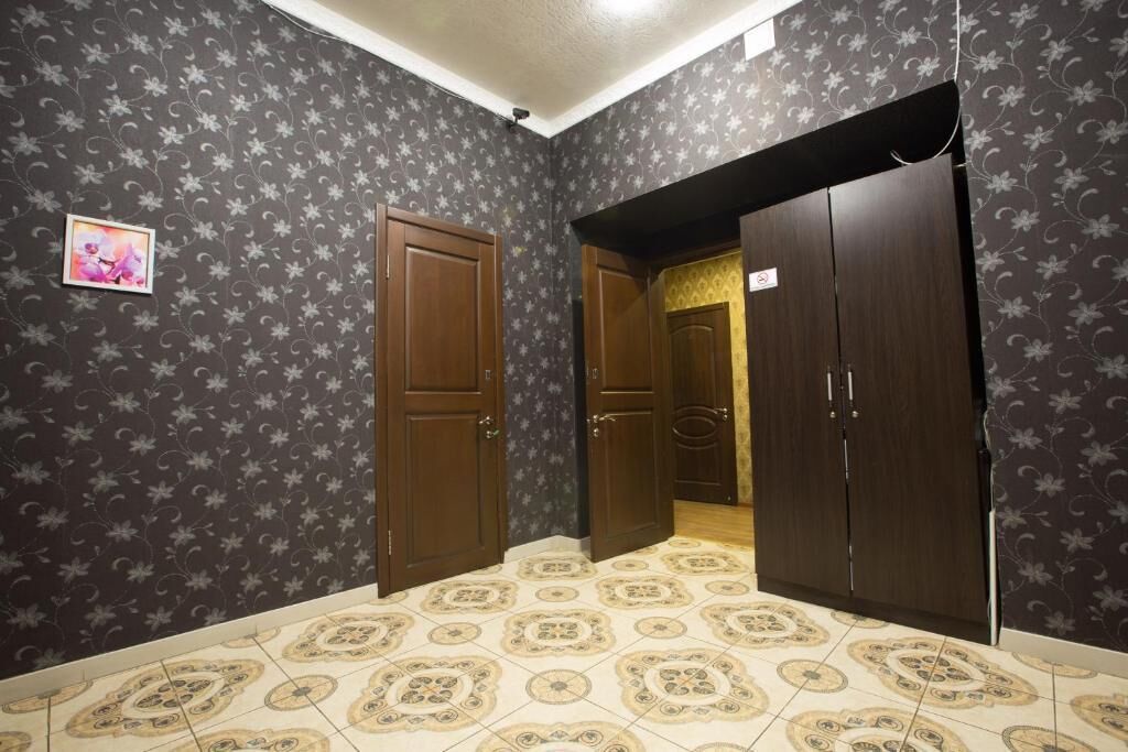 Una habitación con papel tapiz estampado, suelo de baldosas y puertas de madera.