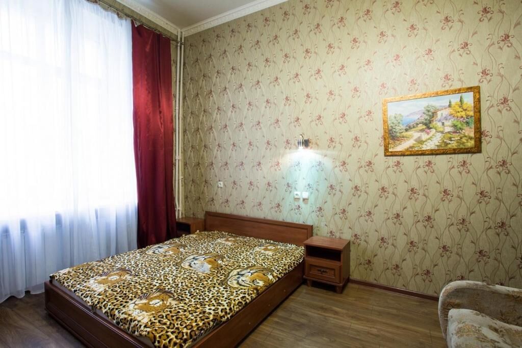 A bedroom with a bed, wooden nightstand, and a wall-mounted lamp.