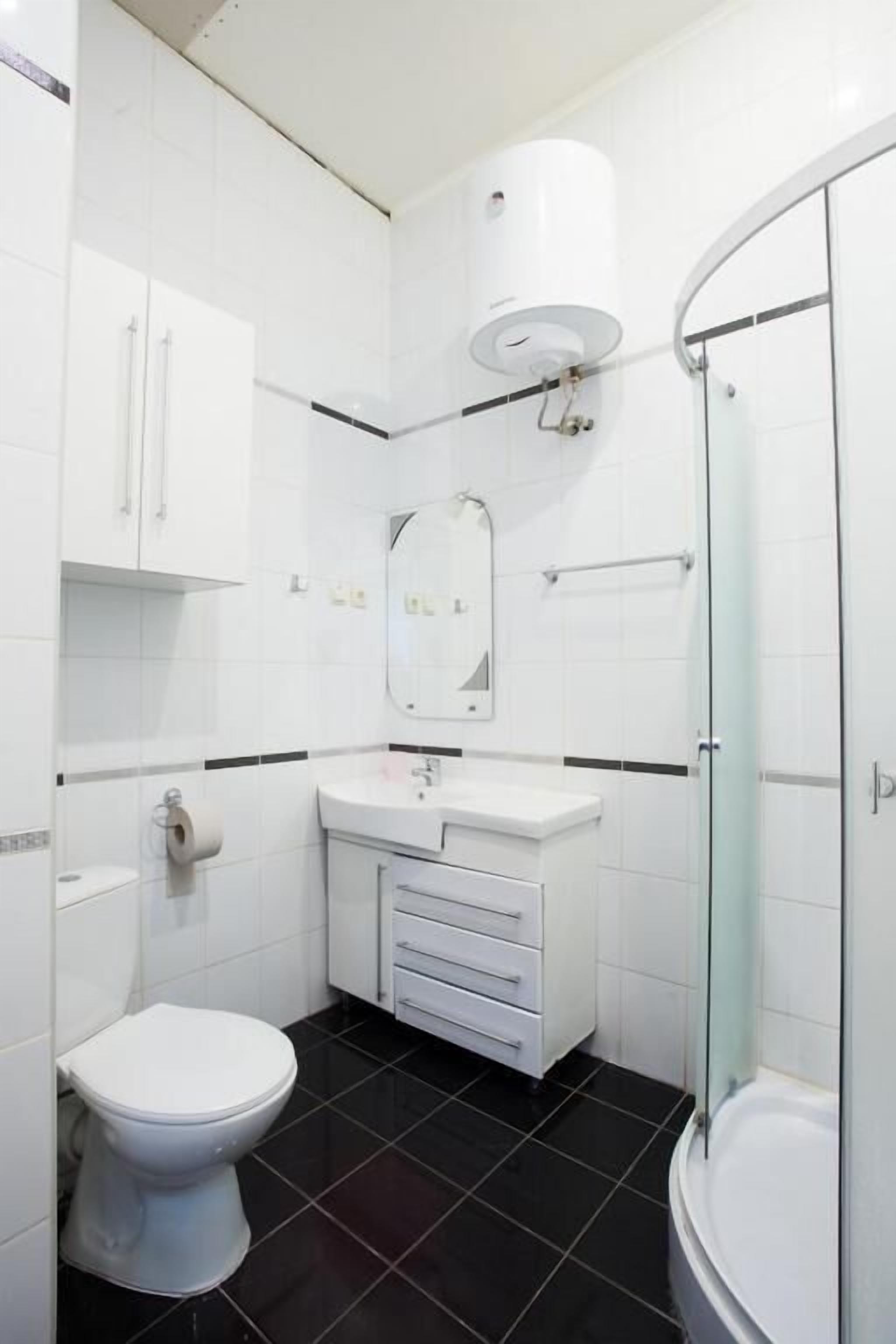 A modern bathroom with a toilet, sink, mirror, and shower.