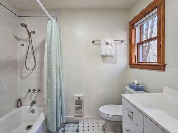 Ein Badezimmer mit Badewanne, Dusche, Toilette und einem Fenster.