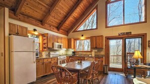 A spacious kitchen with wooden cabinets, a dining table, and chairs.