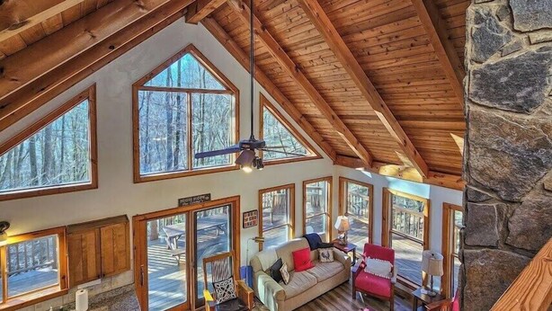 A spacious interior with high ceilings, large windows, and a stone wall.