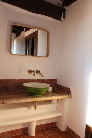 Une salle de bain avec un lavabo en céramique verte, un bac blanc et un miroir au-dessus.