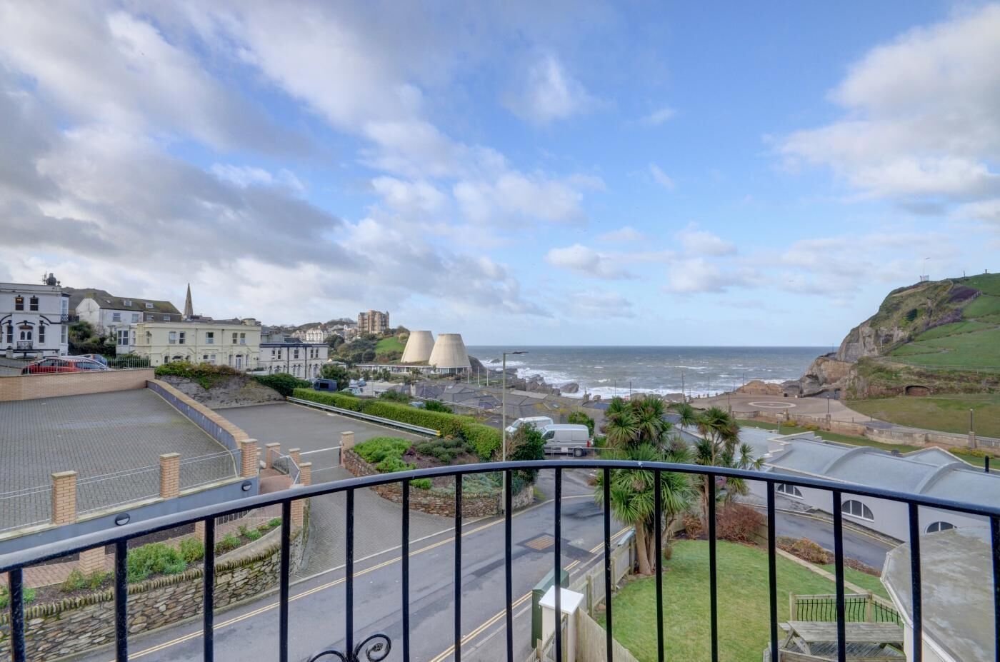 Uma vila costeira com vista para o mar, edifícios e uma área de estacionamento.