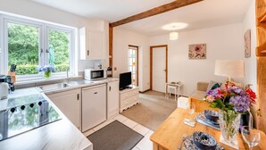 A modern kitchen with a microwave, sink, and dining area with a table set for two. - 1 Bed in East Down (oc-kincot) (East Down)