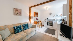 A living room with a sofa, a dining table, a kitchen with a stove, and a TV. - 1 Bed in East Down (oc-kincot) (East Down)