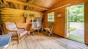 A wooden cabin interior with a table, two chairs, a window, and tennis rackets on the wall. - 1 Bed in East Down (oc-kincot) (East Down)