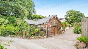 A wooden building with a sloped roof, a gated entrance, and a garden area with potted plants. - 1 Bed in East Down (oc-kincot) (East Down)