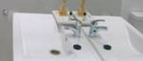 A bathroom with a white sink, a mirror, and a shelf above the sink holding towels.