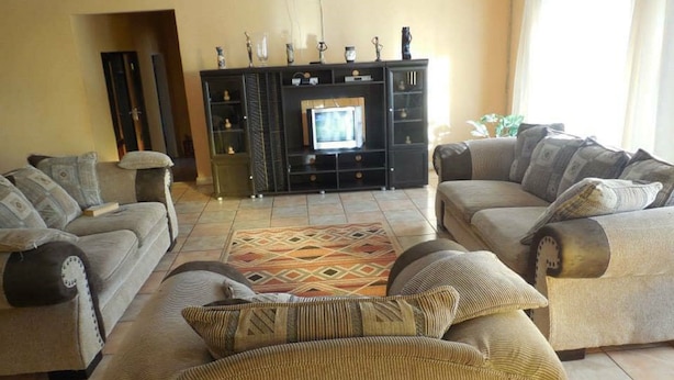 A living room with two sofas, a coffee table, a TV, and a cabinet with decorative items.