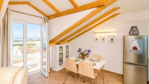 Una zona de menjador amb una taula preparada per a quatre persones, un refrigerador i vista a l'exterior.