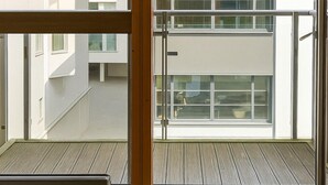 A modern apartment with a large window, a balcony, and a view of neighboring buildings. - Still Life Old Street (London)