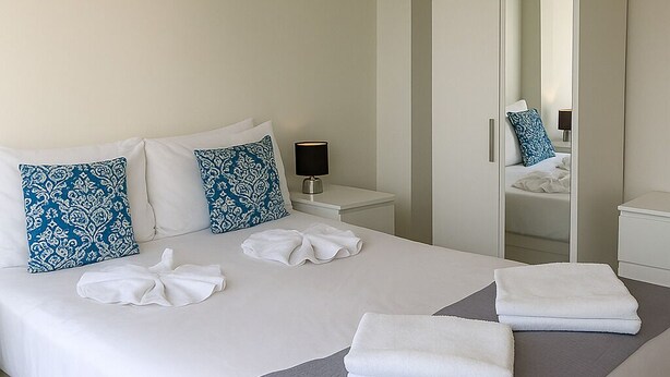 A modern hotel room with a large bed, a wardrobe, a nightstand, and a mirror. - Still Life Old Street (London)