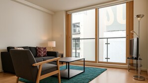 A modern living room with a sofa, a chair, a small table, and a floor lamp. - Still Life Old Street (London)