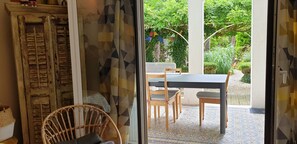 Enjoy a serene view of the garden from this room, featuring a traditional wardrobe, wicker chair, and dining table.