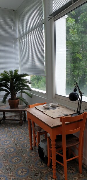 Relax in this inviting space with a large window, a wooden table, and a comfortable chair.
