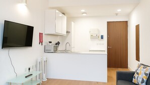 A compact kitchen with a microwave, sink, and a wooden door. - Still Life Chancery Lane (London)