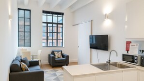 A modern apartment with a kitchen, a sofa, a chair, and a TV. - Still Life Chancery Lane (London)
