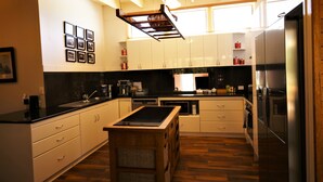 Een moderne keuken met witte kasten, een zwart aanrecht en een houten keukeneiland. Er is een roestvrijstalen koelkast en een hangende lamp.