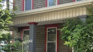 A two-story house with a porch, number 411, and a variety of potted plants.