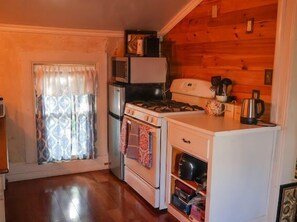 Eine kompakte Küche mit Kühlschrank, Herd, Backofen und Mikrowelle.