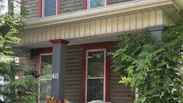 A two-story house with a porch, number 411, and a variety of potted plants.