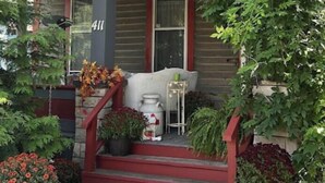 A two-story house with a porch, a staircase, and potted plants.