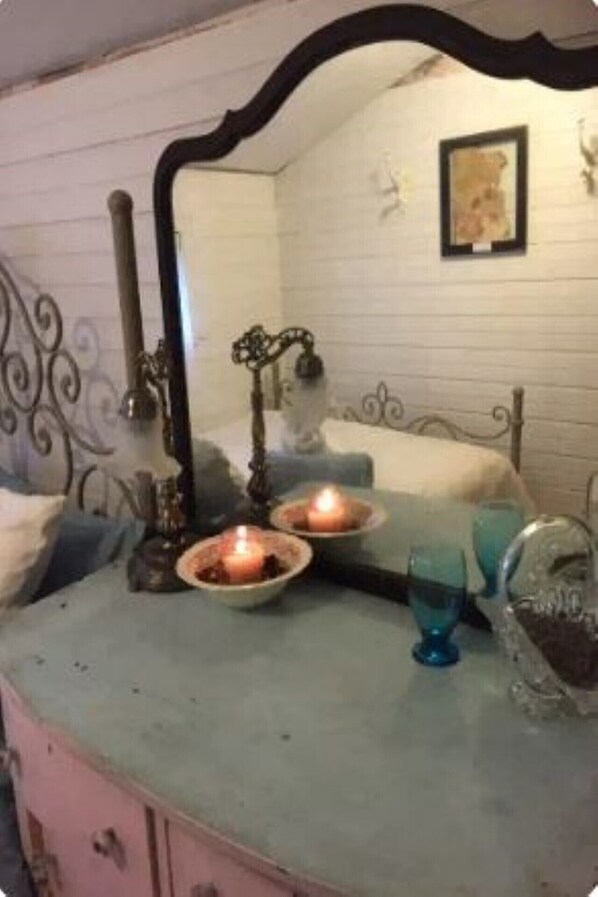 A bathroom with a mirror, a sink, and a bathtub. There are candles on the counter and a blue glass on the side. - Walk to Everything - Servant Room (Niagara Falls)
