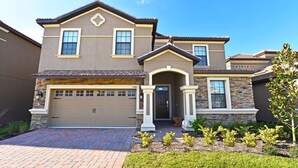 A two-story house with a garage, a stone facade, and a well-maintained front yard. - Champions Gate IHR 3015 (Kissimmee)