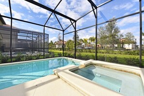 Ein Schwimmbecken mit Whirlpool, umgeben von einer Glaskonstruktion mit Metallrahmen und Blick auf eine Wohngegend.