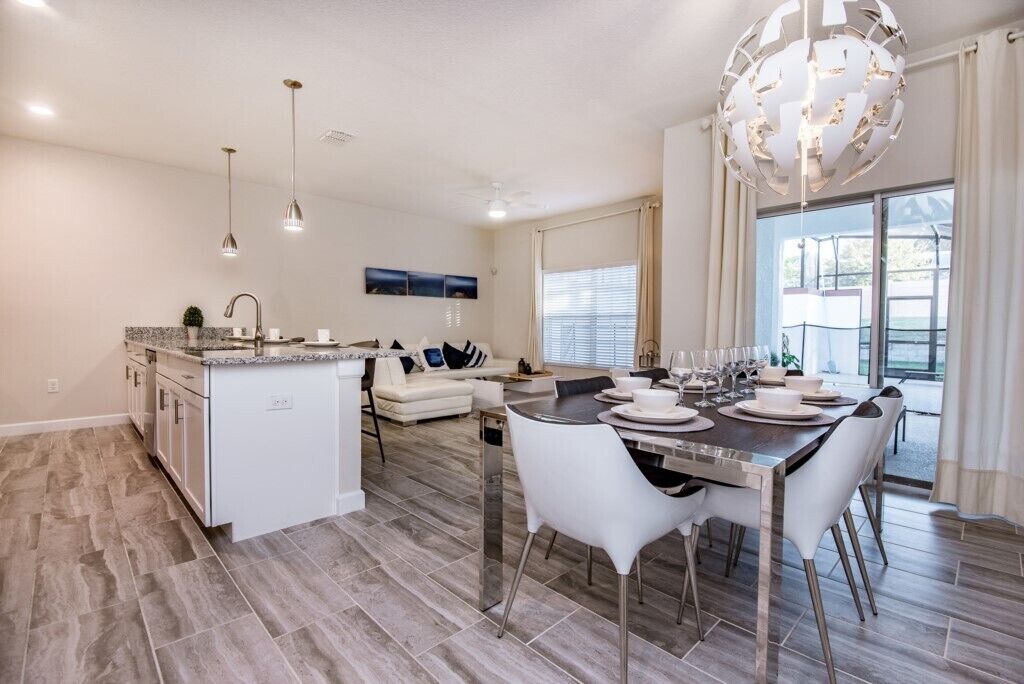 A modern kitchen with a dining area, white cabinetry, and a large island.