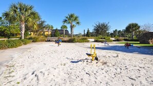 Zona de playa arenosa con equipo de ejercicio y palmeras.