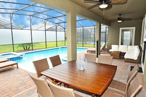 A covered outdoor area with a pool, seating, and a table.