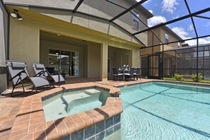 A swimming pool with a hot tub, lounge chairs, and a covered patio area. - Windsor at Westside-2112amwjil (Kissimmee)