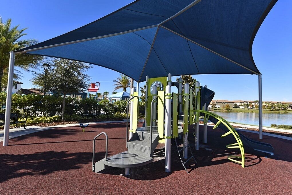 An outdoor playground with a blue canopy, exercise equipment, and a slide.