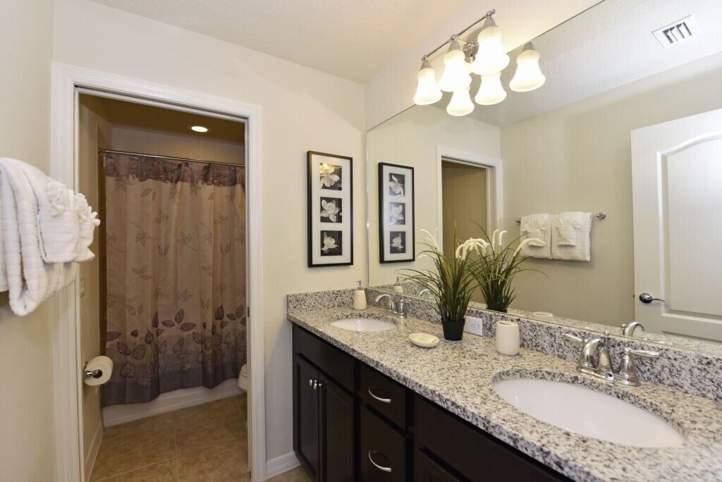 A bathroom with two sinks, a large mirror, and a shower curtain.