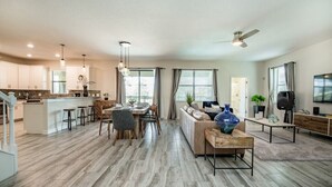 A spacious living area with a dining table, sofas, and a kitchen in the background. - Champions Gate IHR 4029 (Davenport)