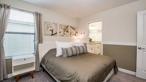 A bedroom with a bed, a nightstand, a window with curtains, and wall art. - Champions Gate IHR 4029 (Davenport)