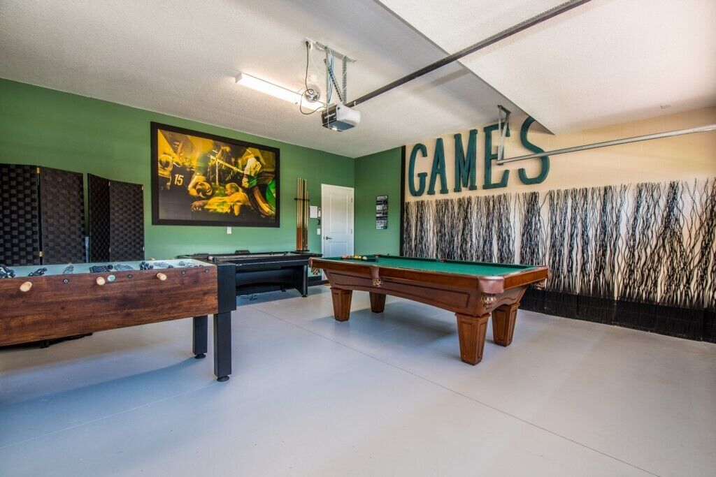 Ett biljardrum med gröna väggar, ett biljardbord och ett bord för bordsfotboll.