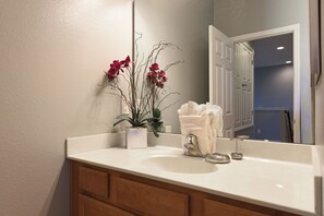 A bathroom with a white sink, a mirror, a potted orchid, and a towel. - Solterra Resort IHR 3050 (Davenport)
