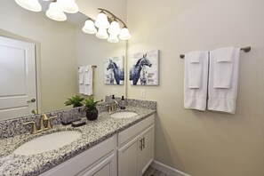 A bathroom with two sinks, a large mirror, and a towel rack. - Champions Gate IHR 3014 (Davenport)