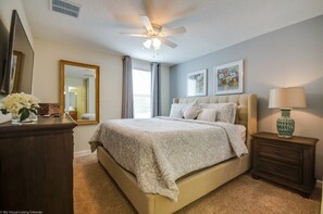 Cozy retreat with a large bed, ceiling fan, and comfortable nightstand.