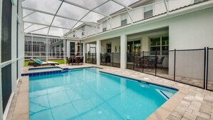 Una piscina con techo de vidrio, rodeada de un patio con mobiliario exterior.