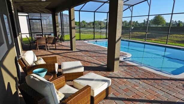 Un patio al aire libre con mobiliario de mimbre y piscina.