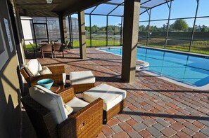 An outdoor patio with wicker furniture and a pool. - Providence IHR 3036 (Davenport)