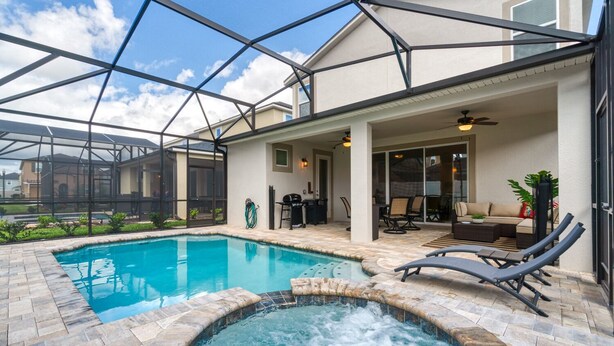 A covered outdoor swimming pool with a hot tub, lounge chairs, and a patio area with outdoor furniture. - Summer Specia 4 BRM W Pool (Kissimmee)