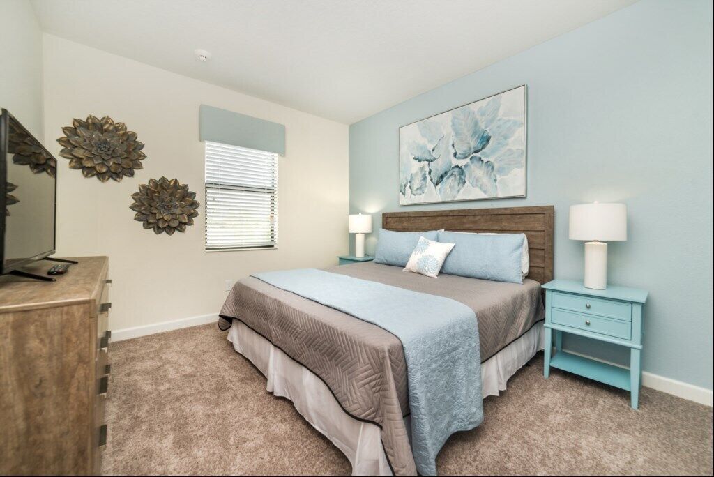Un dormitorio con cama, mesitas de noche, cómoda y decoración en la pared.